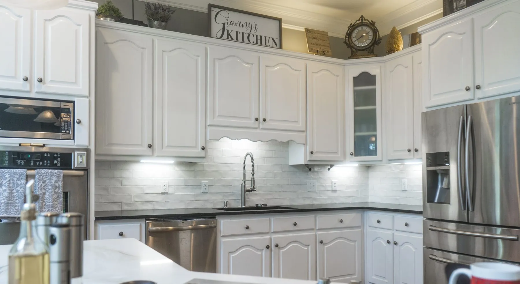 Marble-look subway tile backsplash running the full counter run in a white kitchen with granite countertops