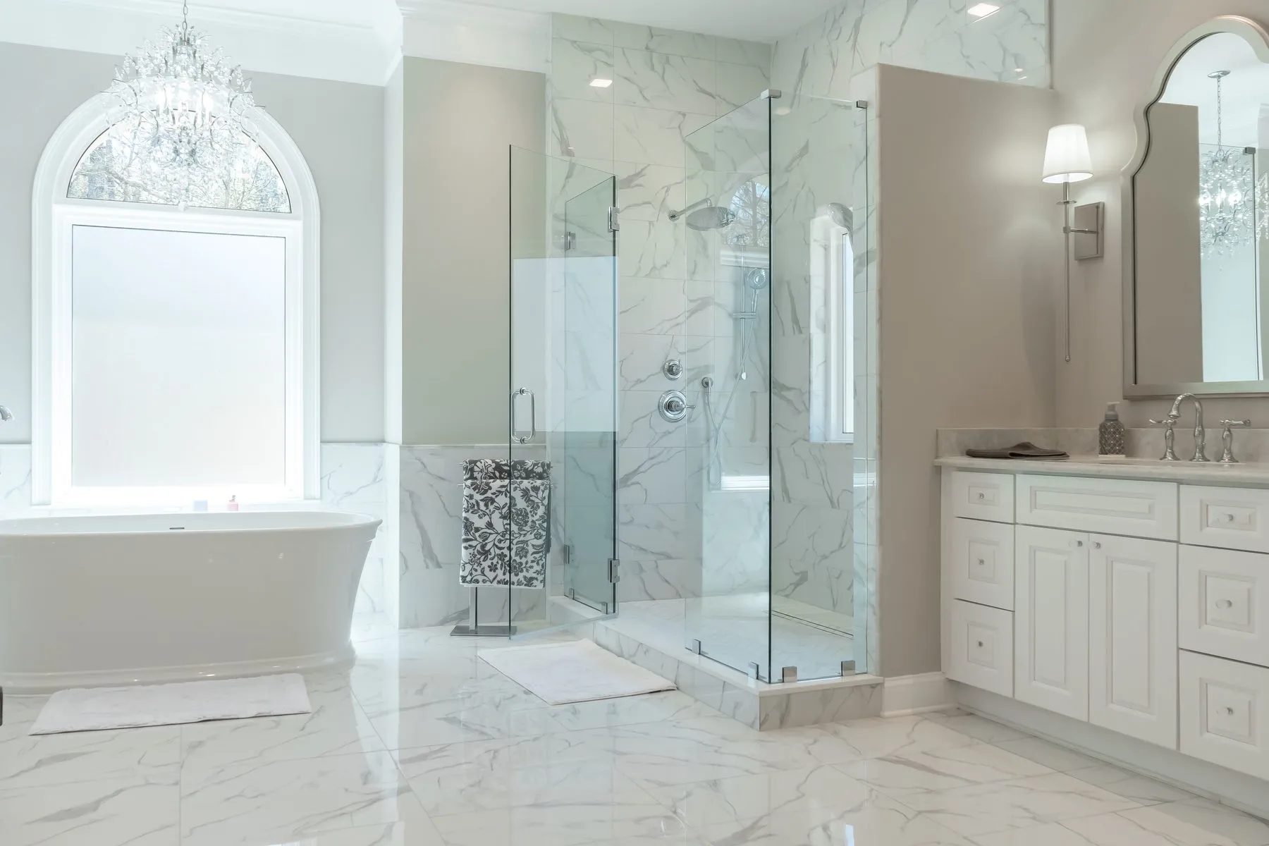 Frameless glass corner shower in book-matched marble-look porcelain with a marble curb and threshold