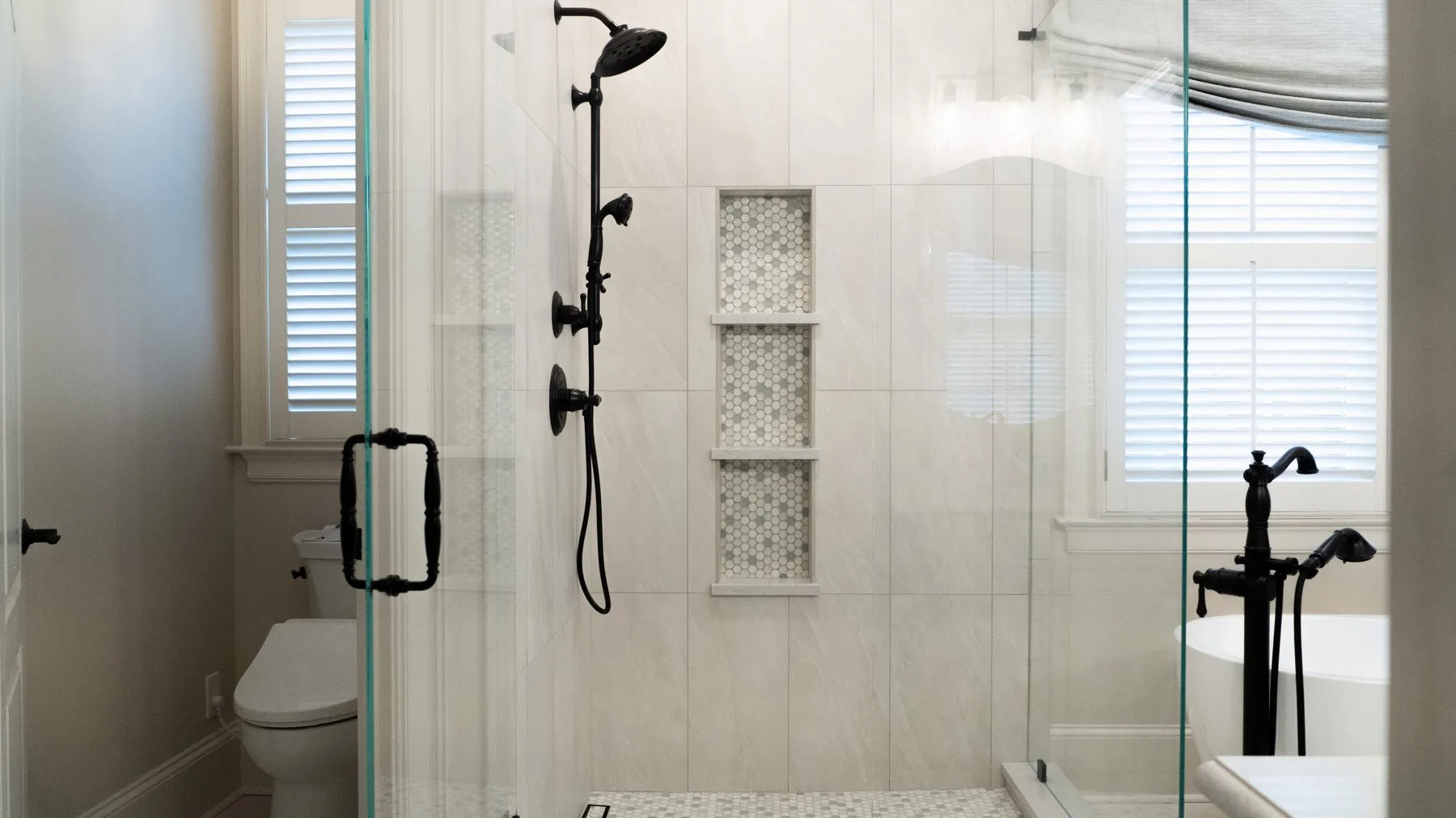 Walk-in shower with a stacked three-shelf niche in mosaic tile and matte black fixtures