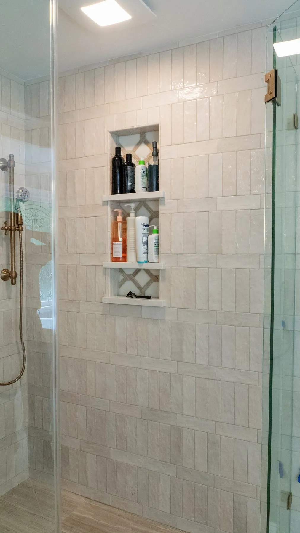 Two-shelf shower niche with a lattice mosaic back, set into travertine-look porcelain