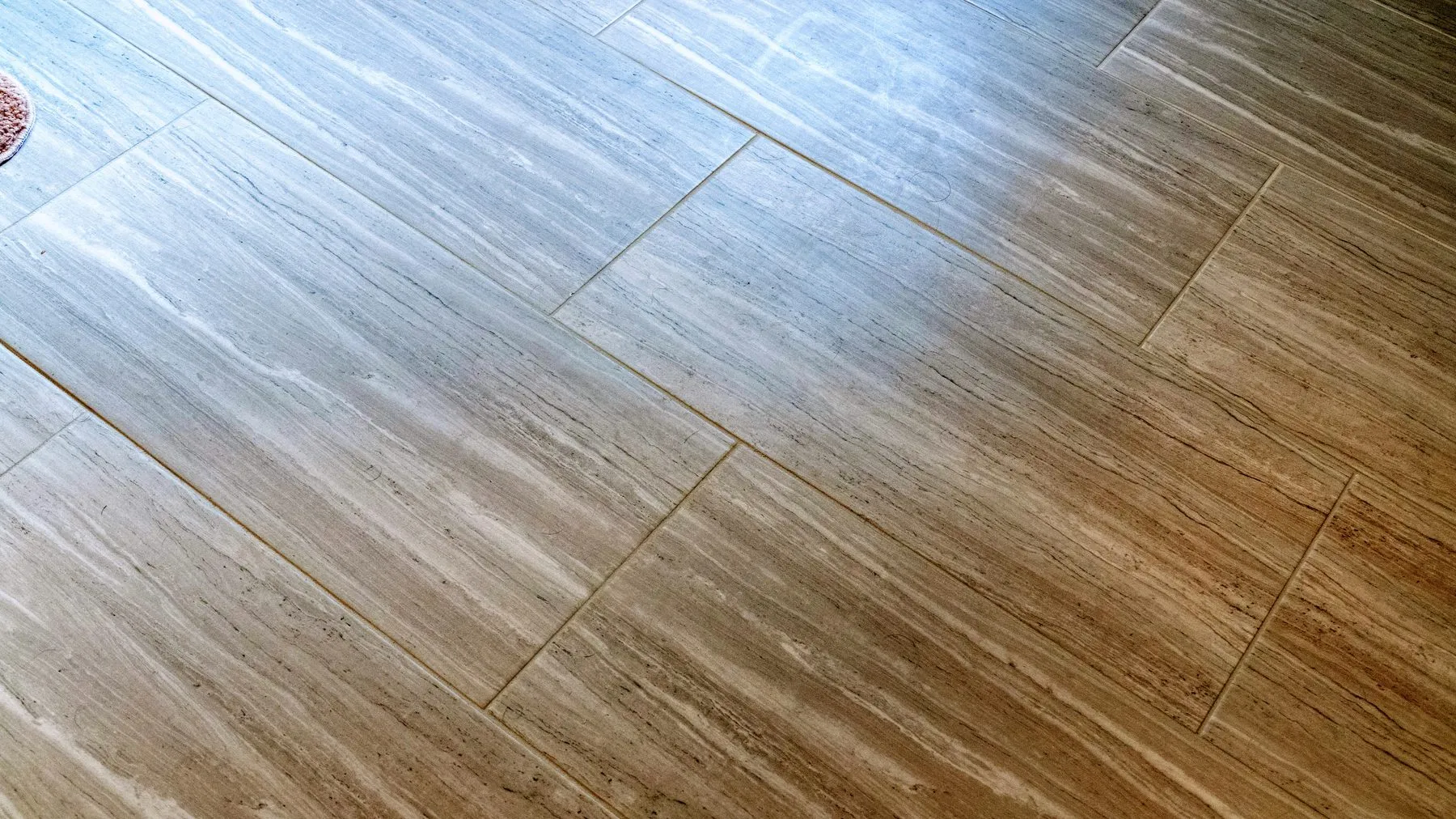 Travertine-look porcelain floor laid in a running bond with tight, even grout joints