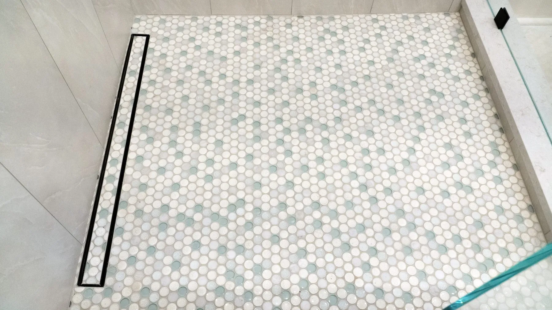 Hexagon mosaic shower floor sloped to a linear drain set flush against the wall