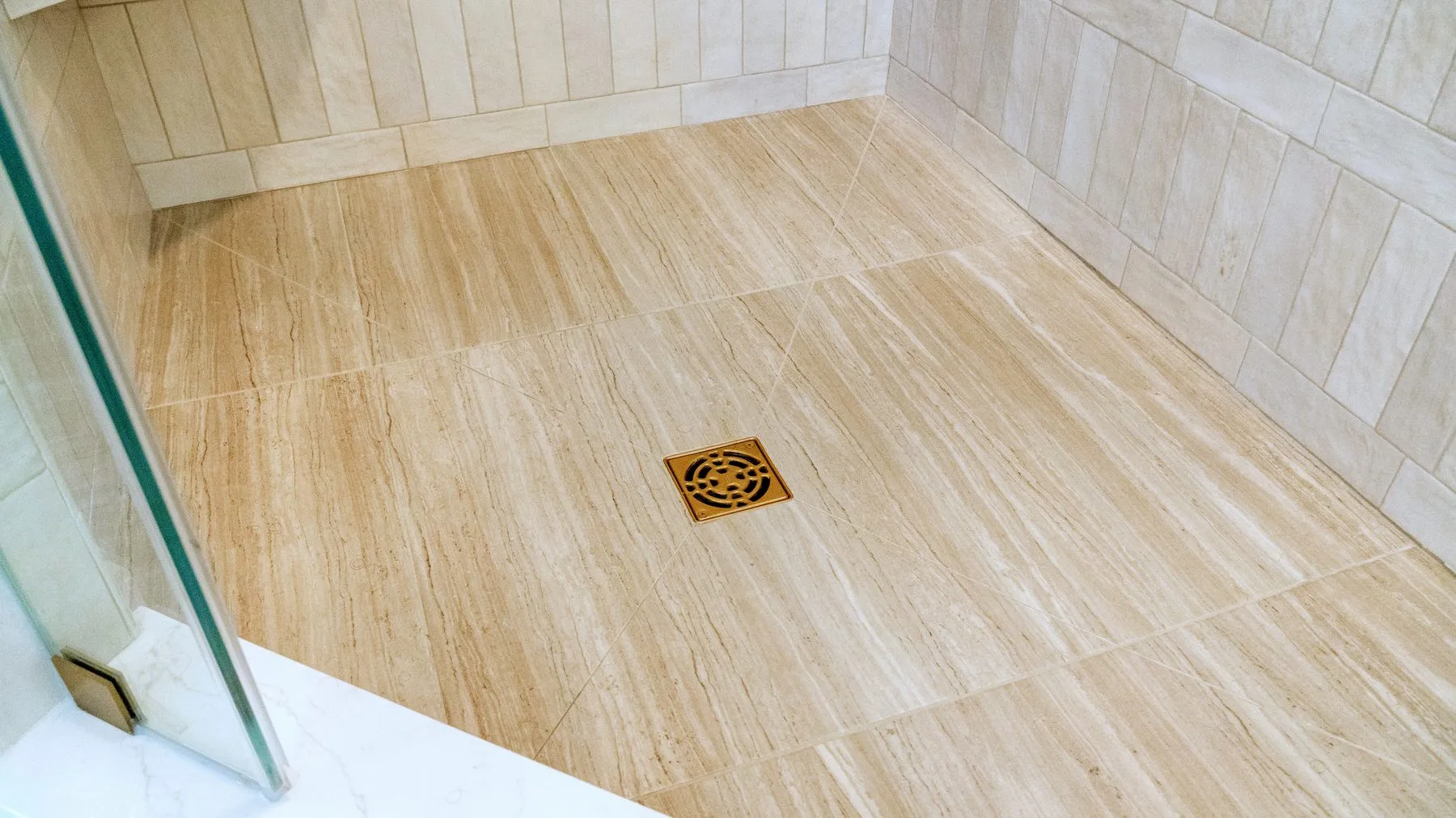 Travertine-look shower pan sloped to a square brass centre drain