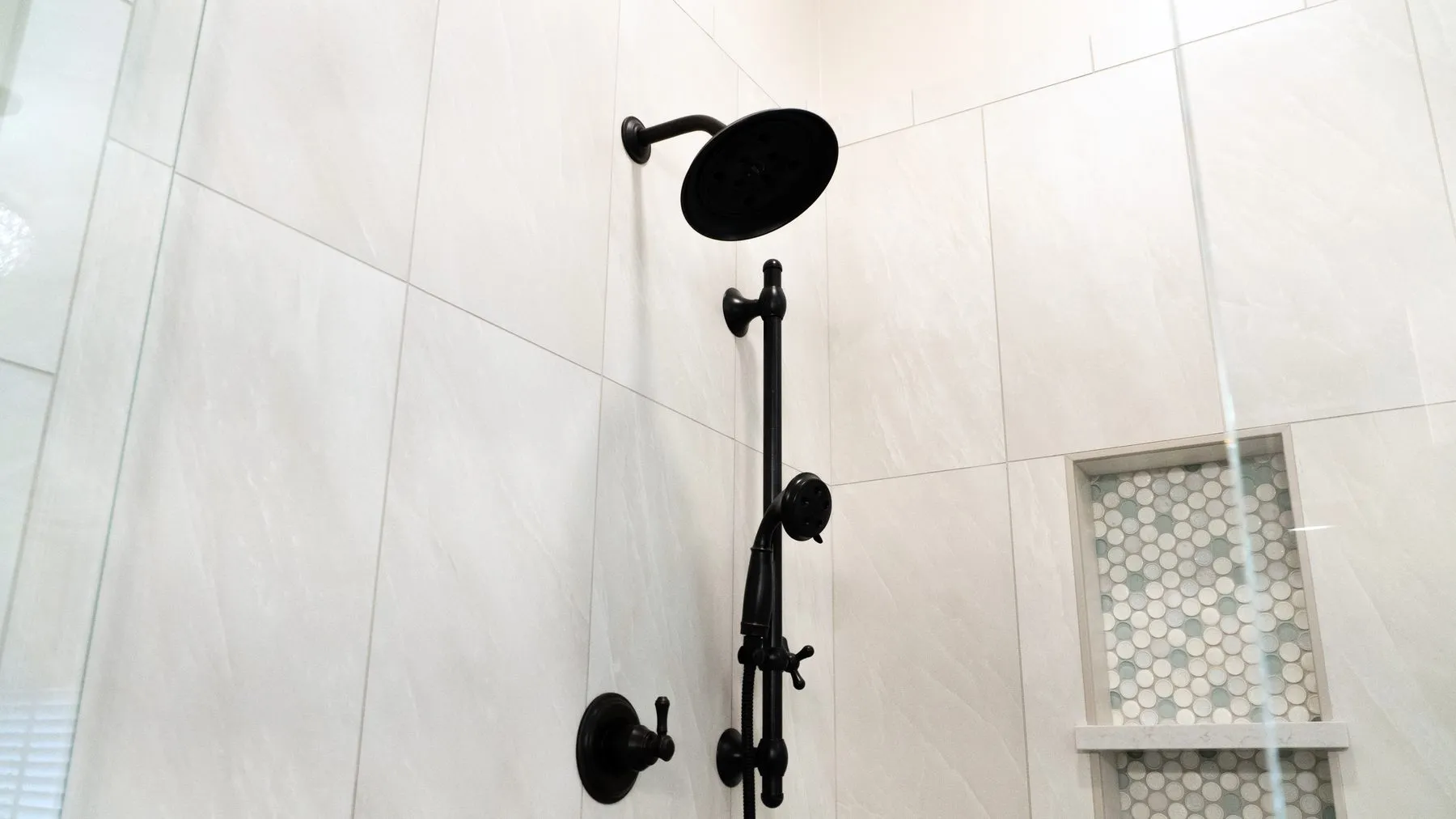 Shower fixtures and a recessed niche set into large-format porcelain wall tile