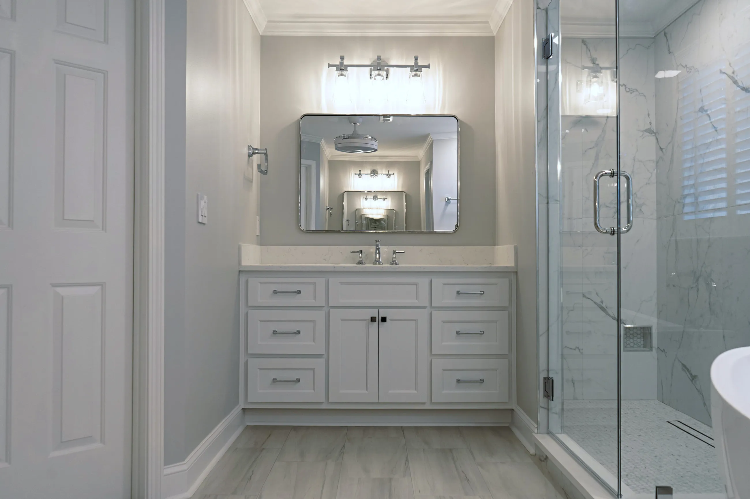 Suite bathroom with a custom vanity, framed mirror and wall sconces