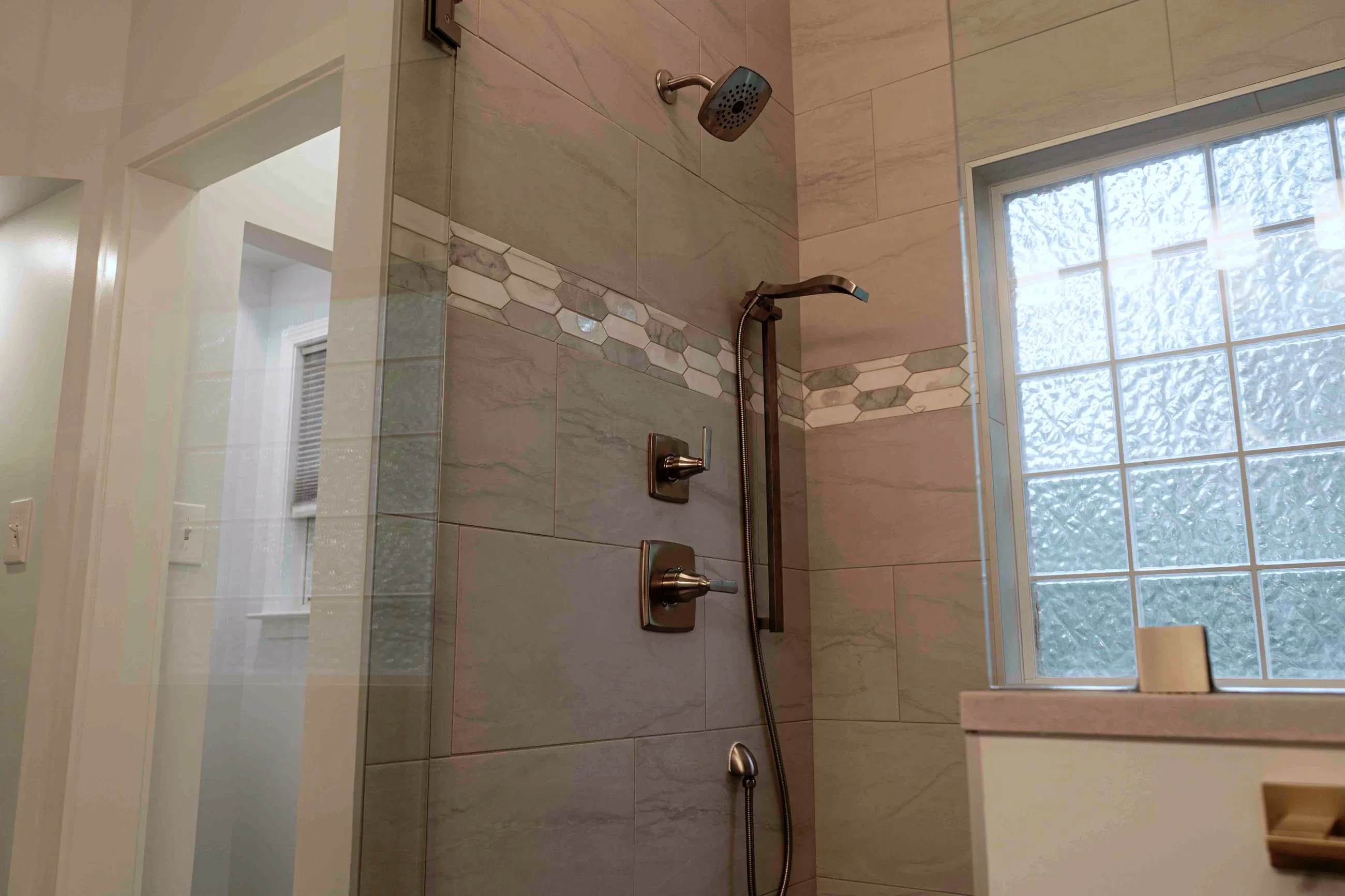 Walk-in shower with a mosaic tile band and bronze fixtures, Peachtree City