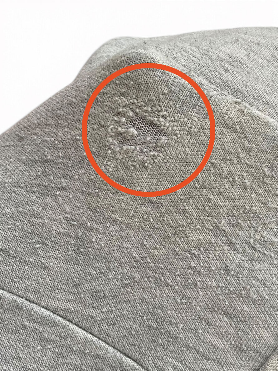 Grey knit worn thin in one spot, circled