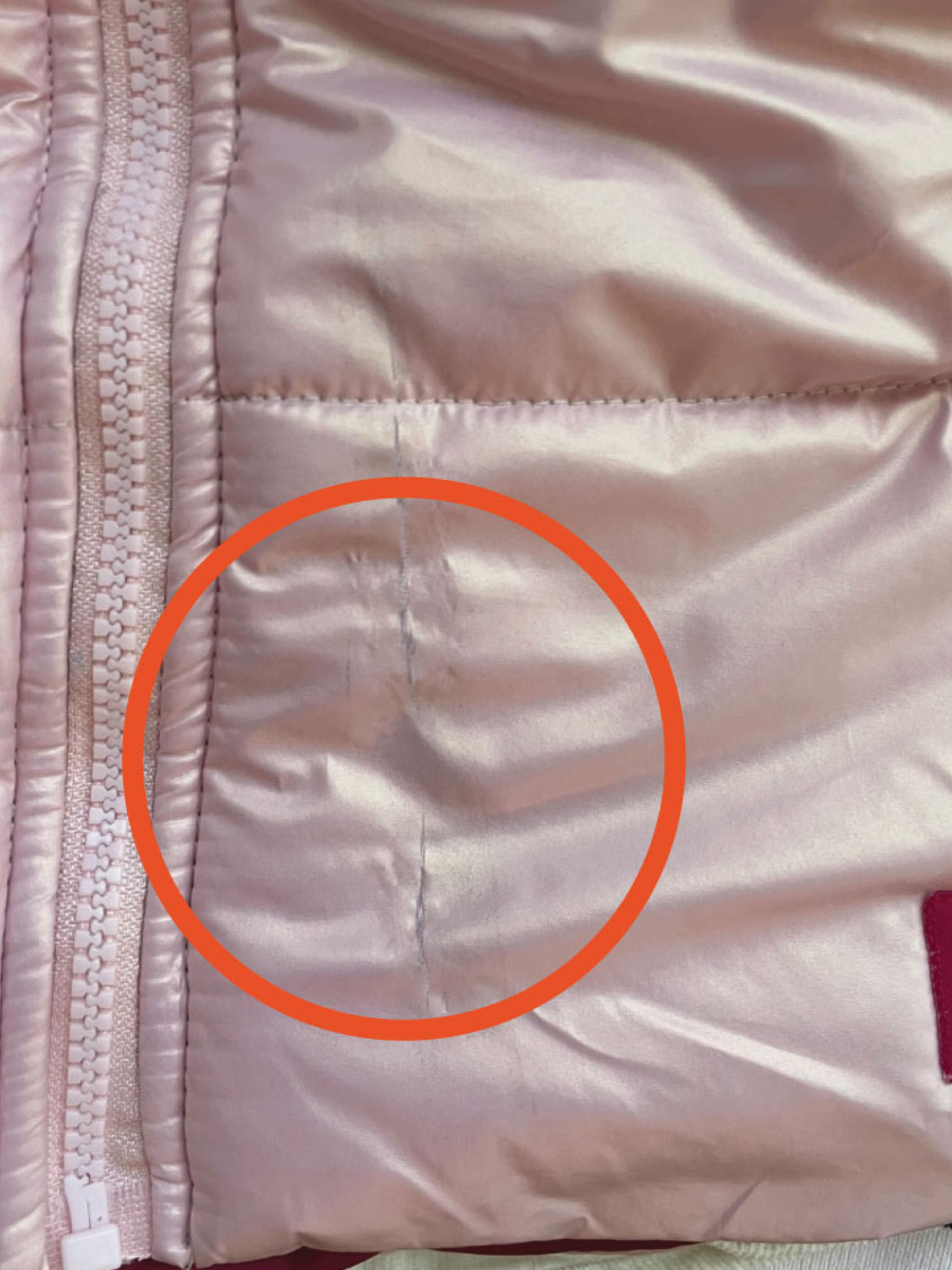Pink puffer jacket with a visible mended rip, circled