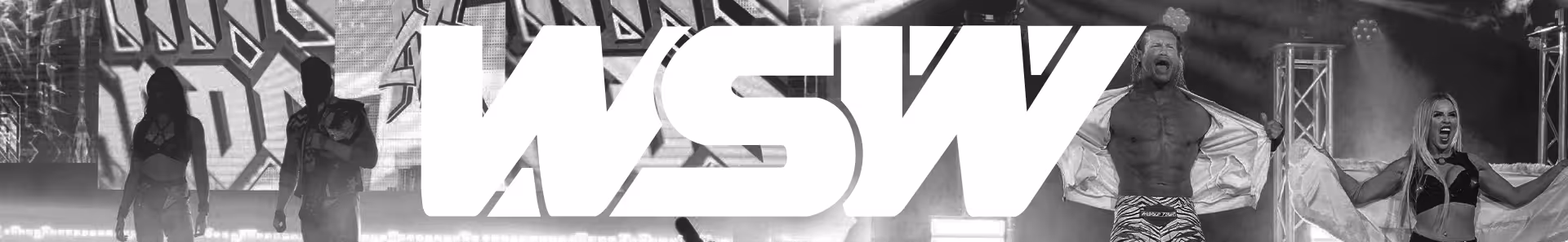 Four energetic wrestlers posing and celebrating on a stage with lighting trusses and a background screen.