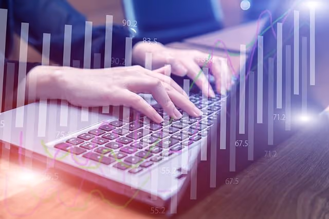 Tuvplāns ar rokām, kas raksta uz portatīvā datora tastatūras, virs kurām uzmontēti caurspīdīgi finanšu stabiņu un līniju grafiki.