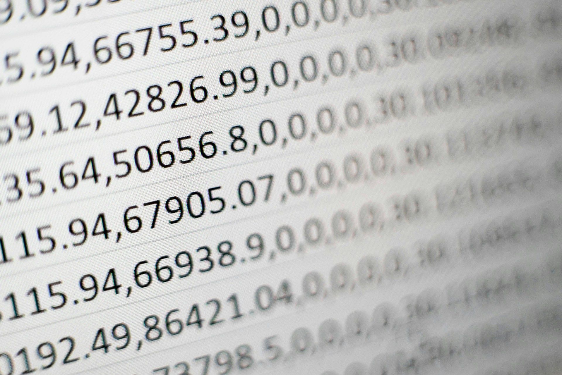 Close-up of rows of a data table with numbers and decimals, part of the table blurred.