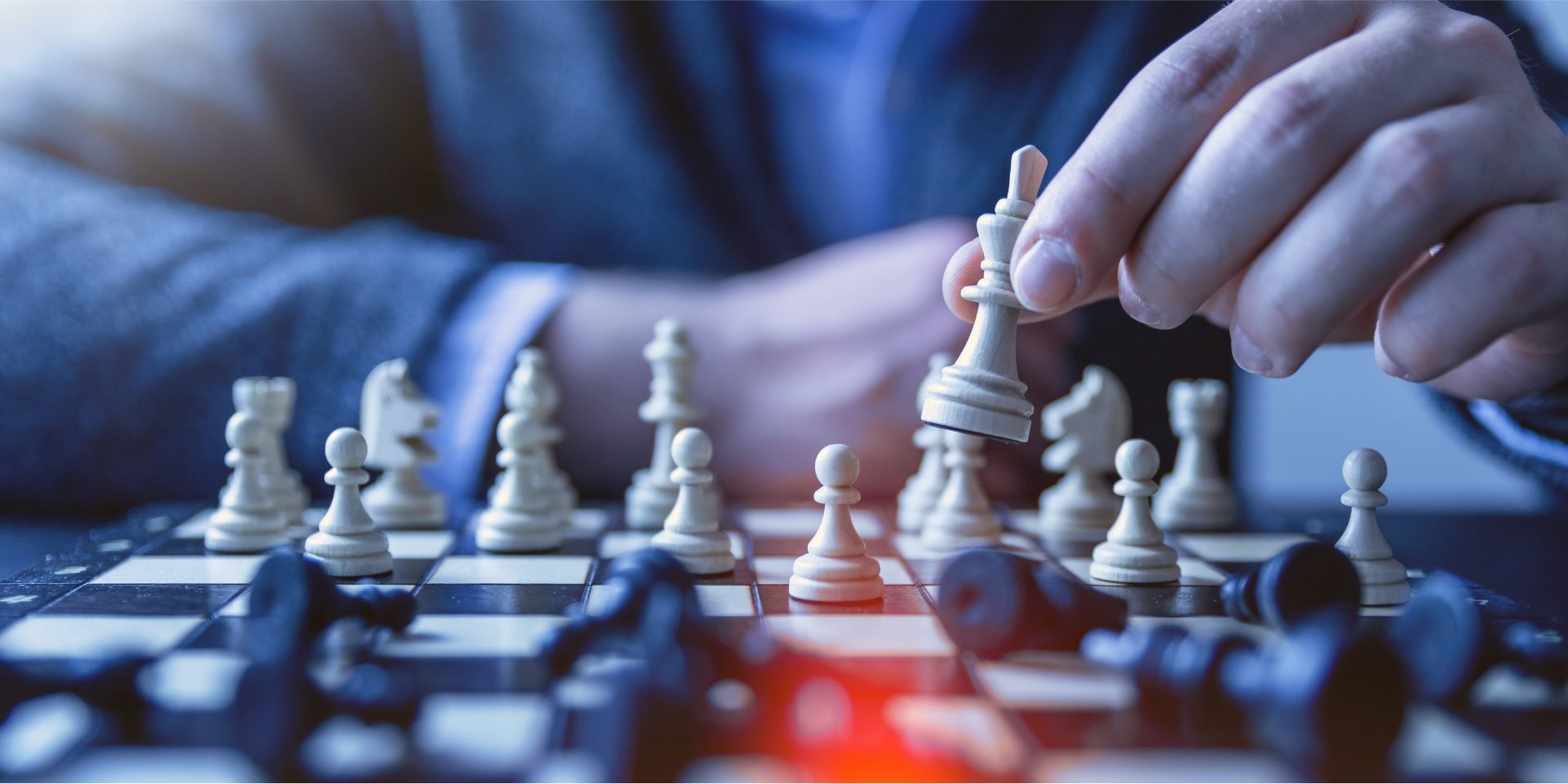 A hand moves a chess piece across a chessboard.