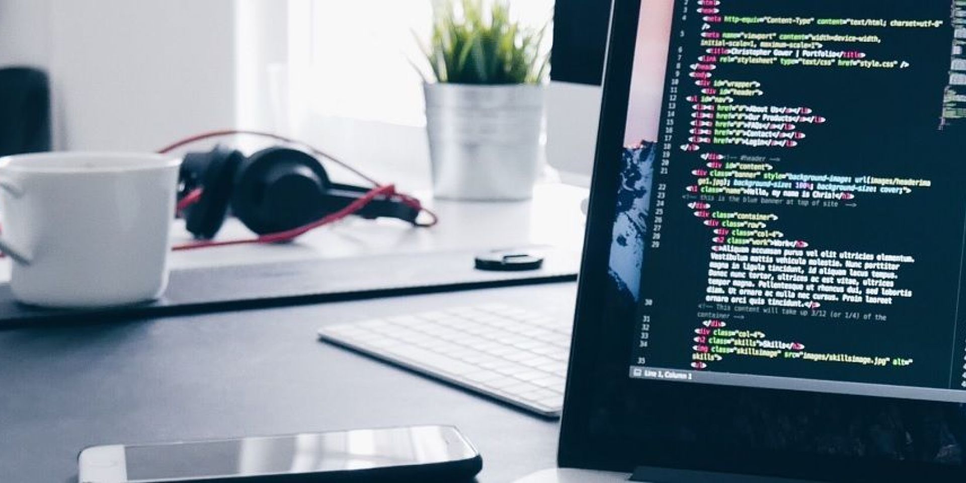A desk with a computer showing programming code, with an office setting in the background.
