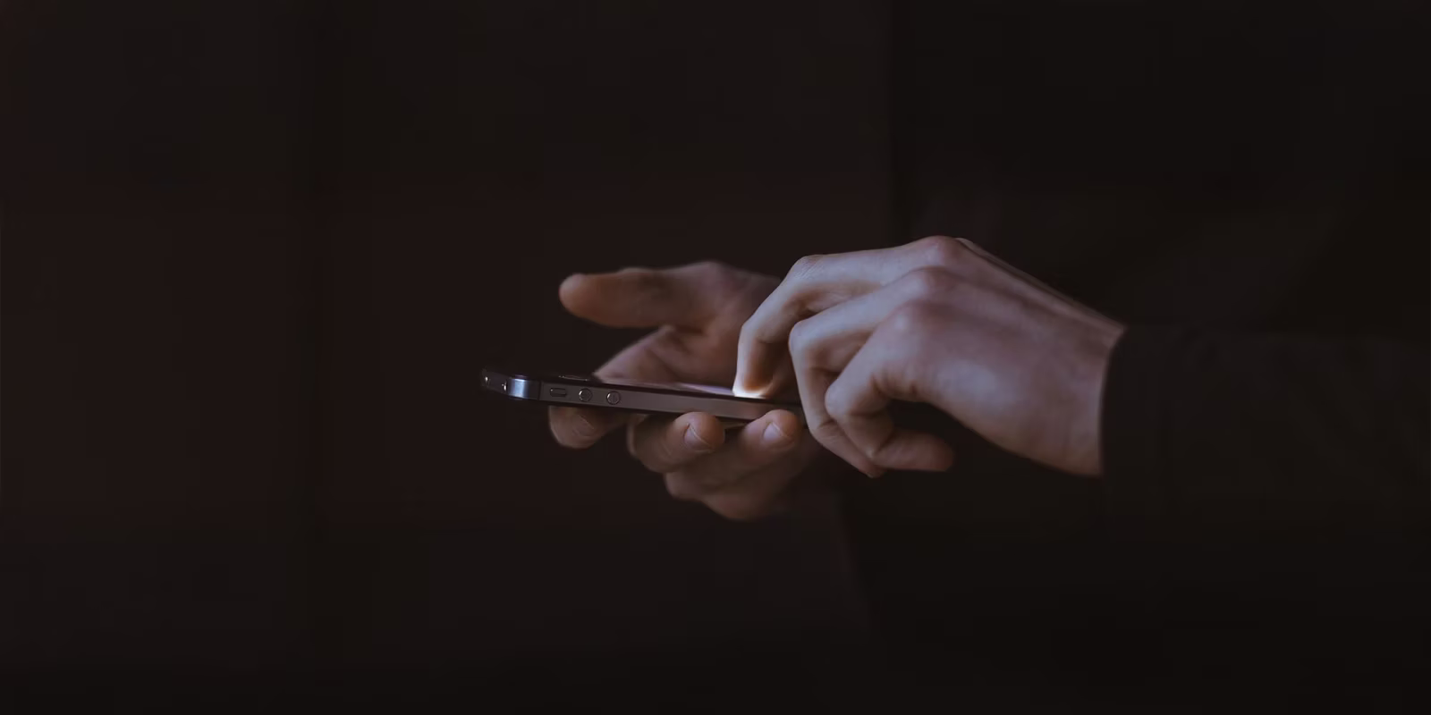 Atvērtas klēpjdatora tastatūras apgaismojums tumsā ar sarkani zilu gaismu.
