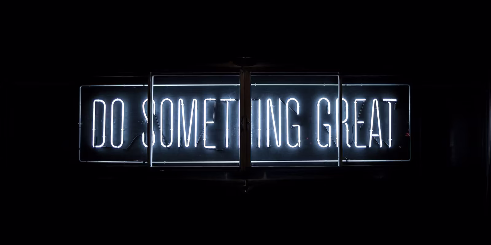 Neona gaismas zīme ar uzrakstu “DO SOMETHING GREAT”.
