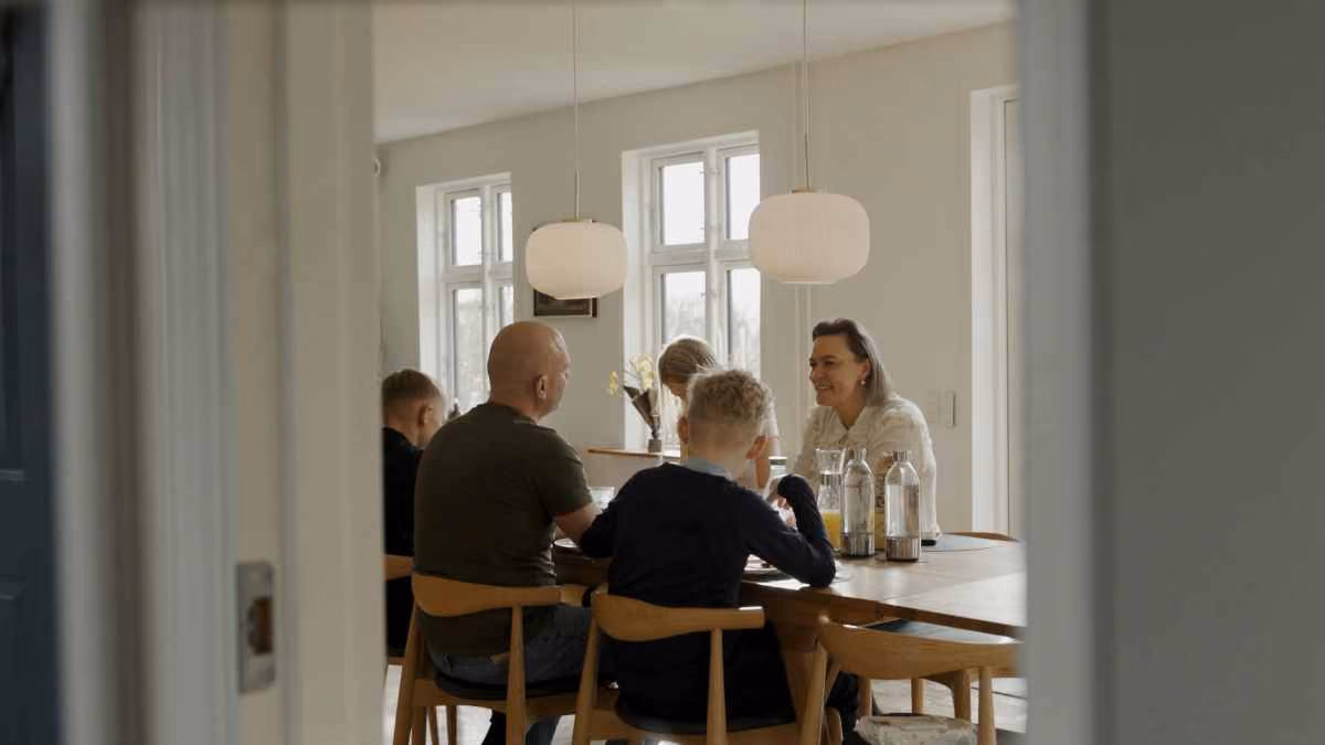 Ģimene kopīgi pavada laiku pie pusdienu galda mājīgā un gaišā ēdamistabā.