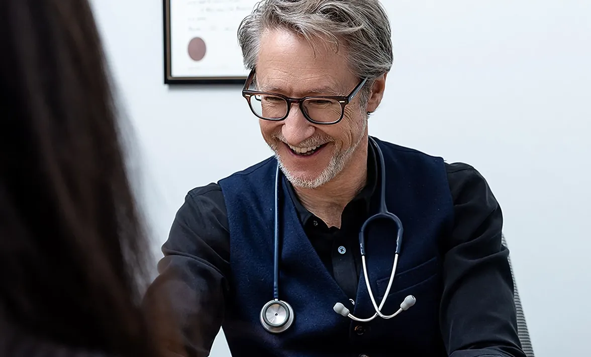 Doctor with stethoscope smiling during a patient consultation