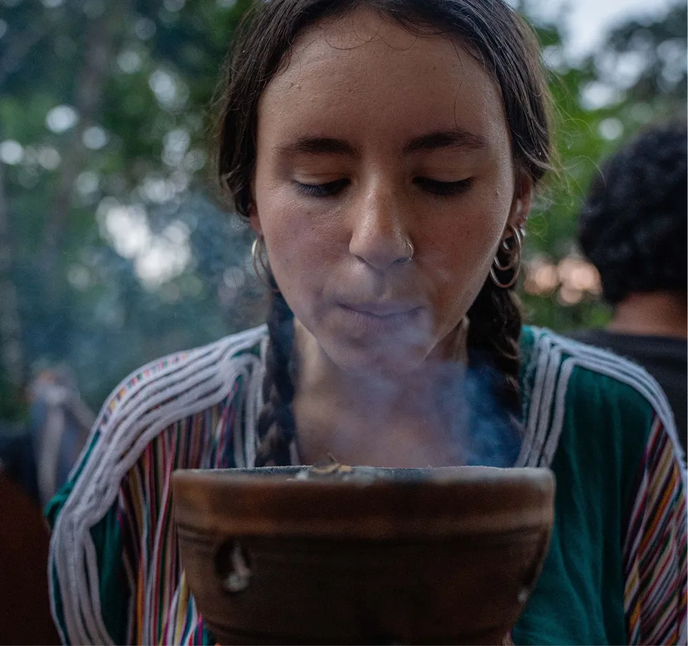 Woman participating in a traditional plant medicine ceremony exhaling smoke