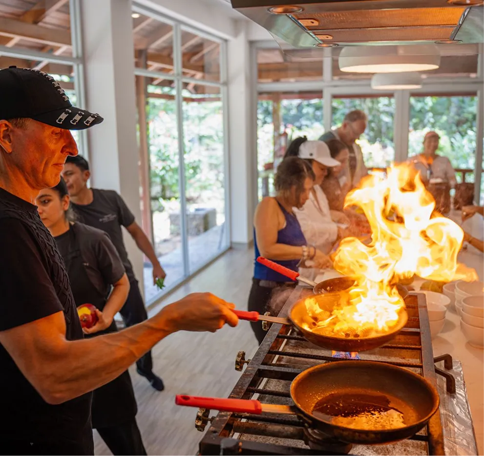 Chef preparing a flambé dish during a cooking experience at the retreat