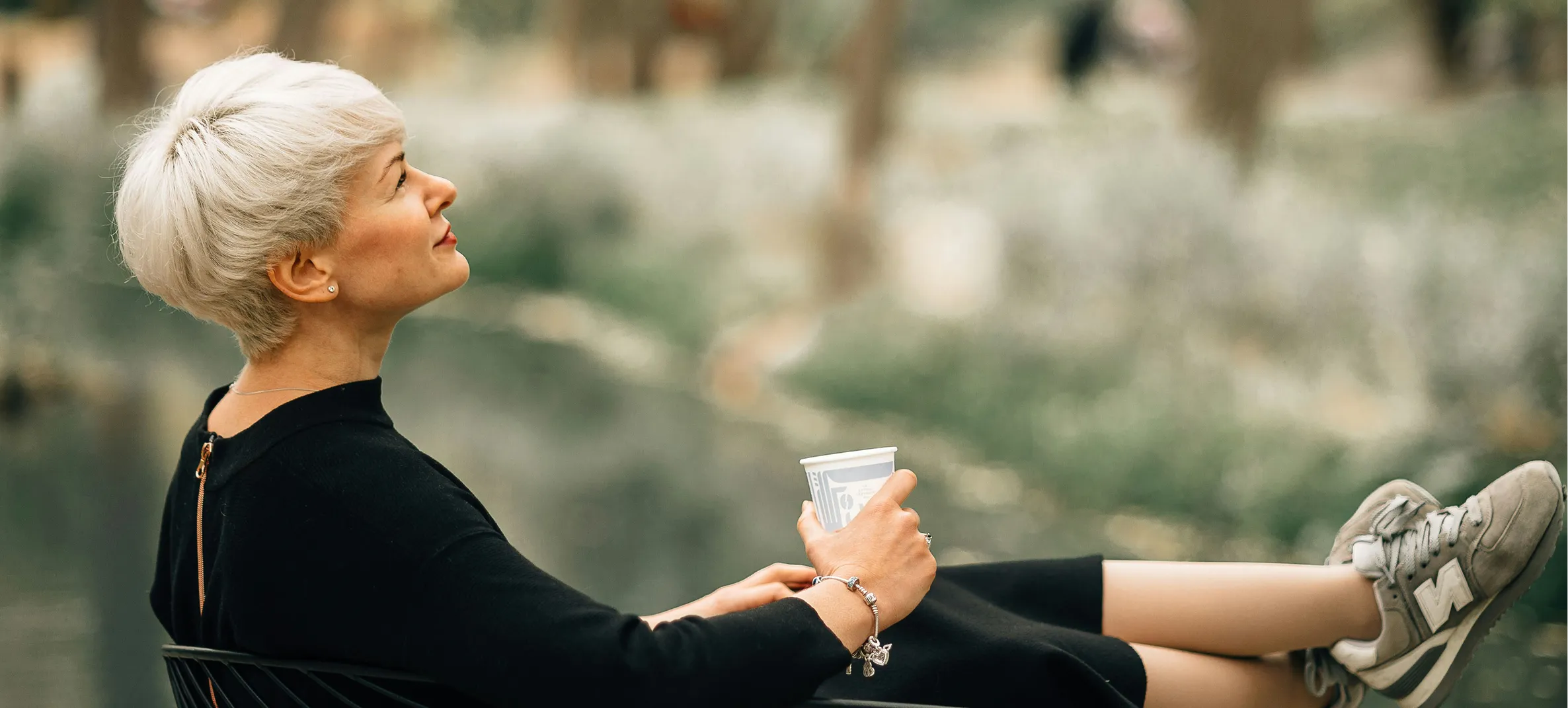 Elegant older woman with white hair looking upward in a peaceful outdoor setting