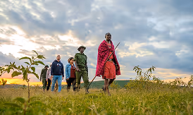 Retreat group walking with Maasai warriors at sunset on the African plains