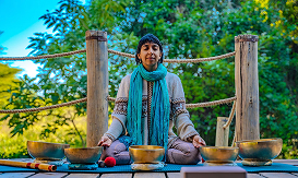 Woman meditating with Tibetan singing bowls in an outdoor nature setting