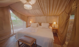Luxury safari tent bedroom with white bedding and warm ambient lighting