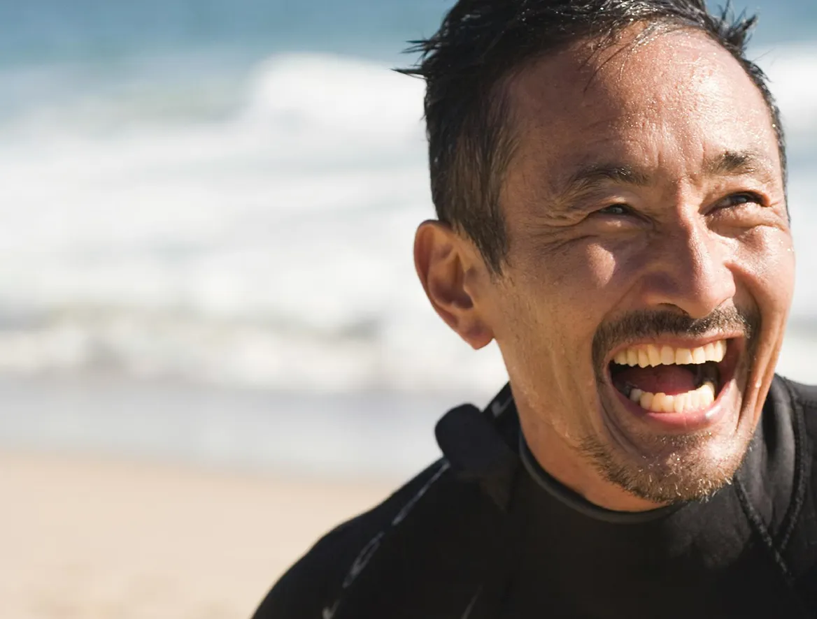 Man smiling and laughing on a beach