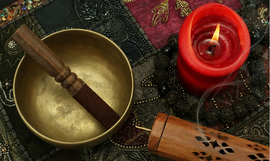 Tibetan singing bowl with mallet beside a lit red candle