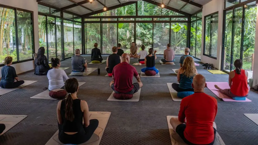 Group meditation session inside a glass greenhouse in the Amazon rainforest