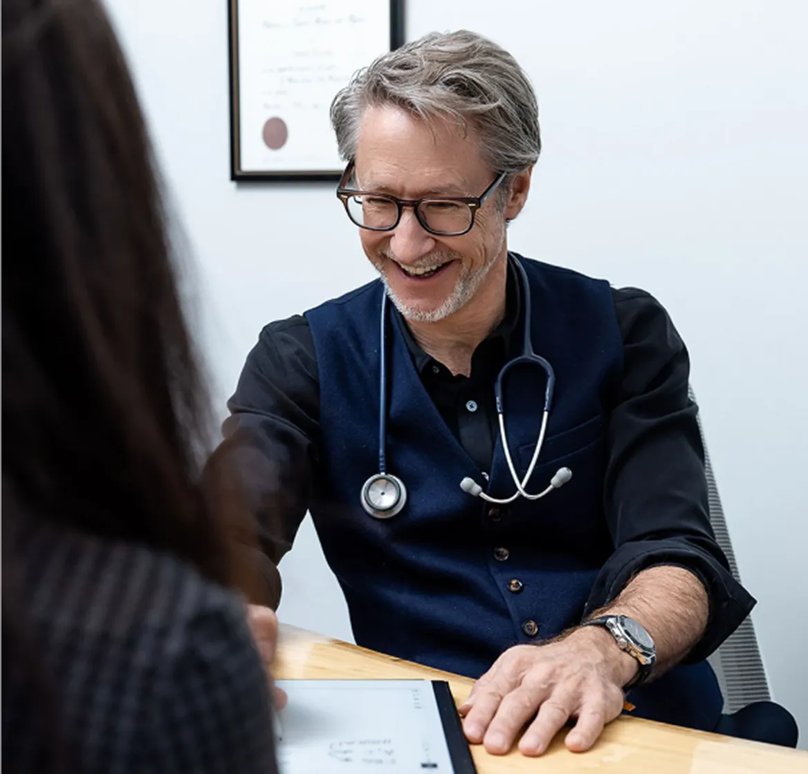 Doctor with stethoscope smiling warmly during a patient consultation