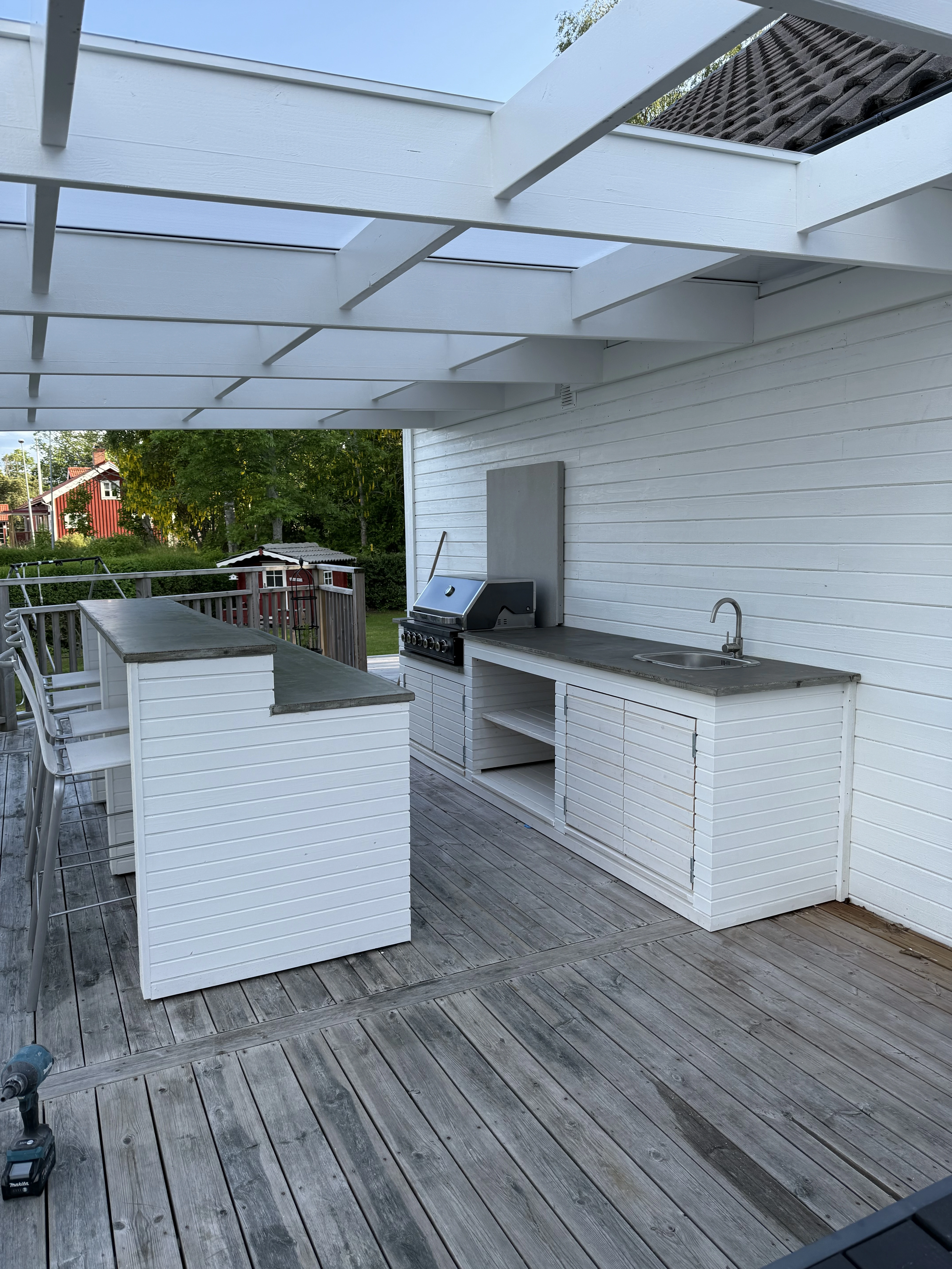 Utekök i vita paneler med köksö i mörk sten