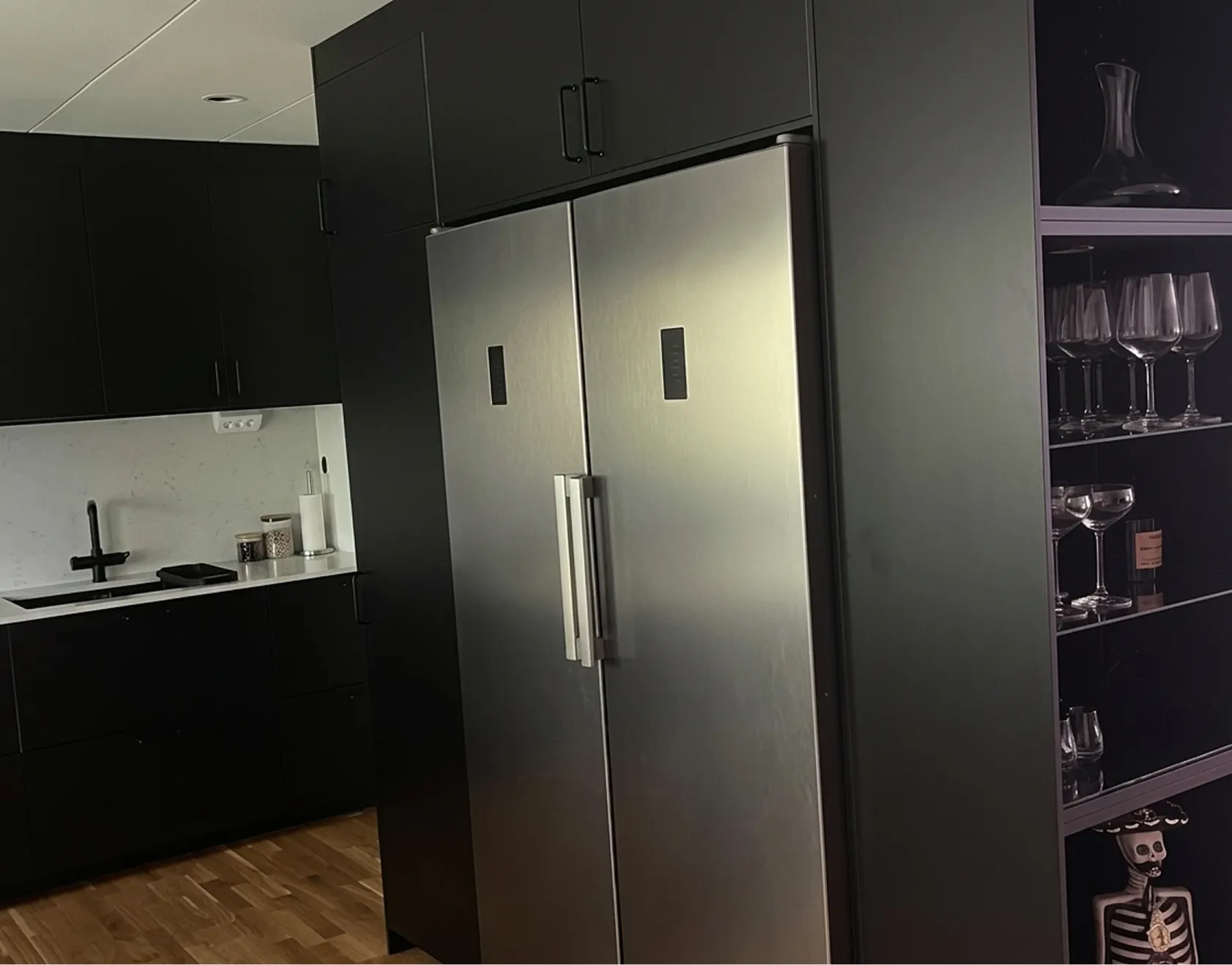 Silvrig inbyggd kyl och frys i mattsvart vägg.