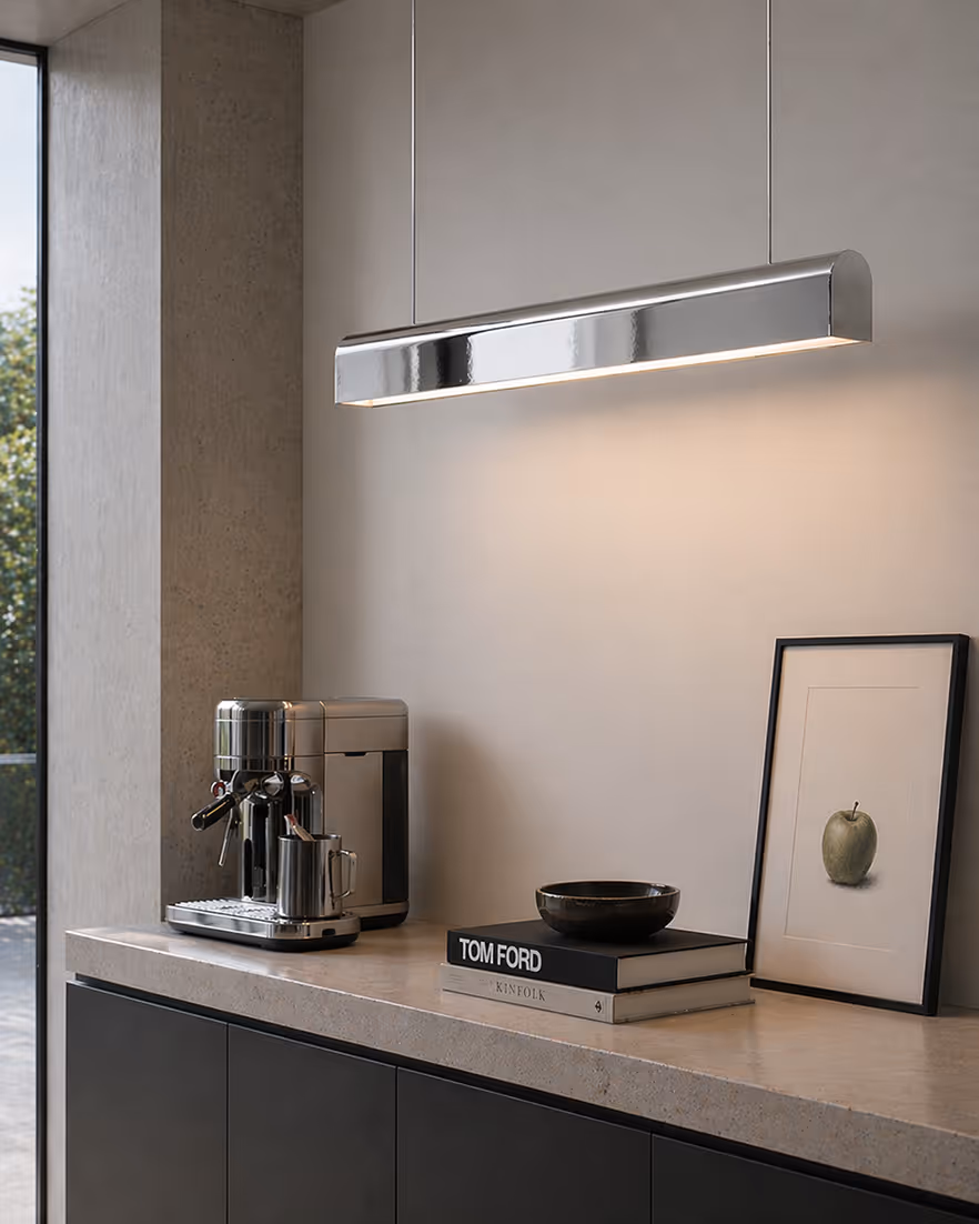 Modern kitchen counter with a stainless steel coffee machine, stacked books, bowl, and framed apple art.