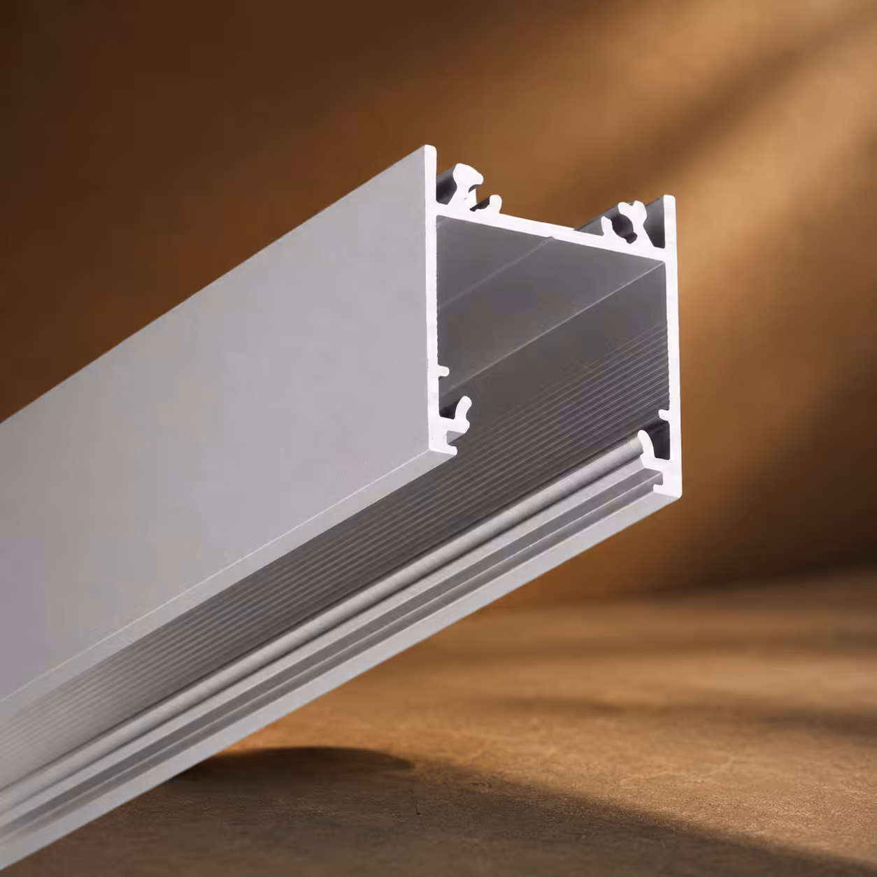Close-up of a silver aluminum profile with grooves and a hollow rectangular shape.