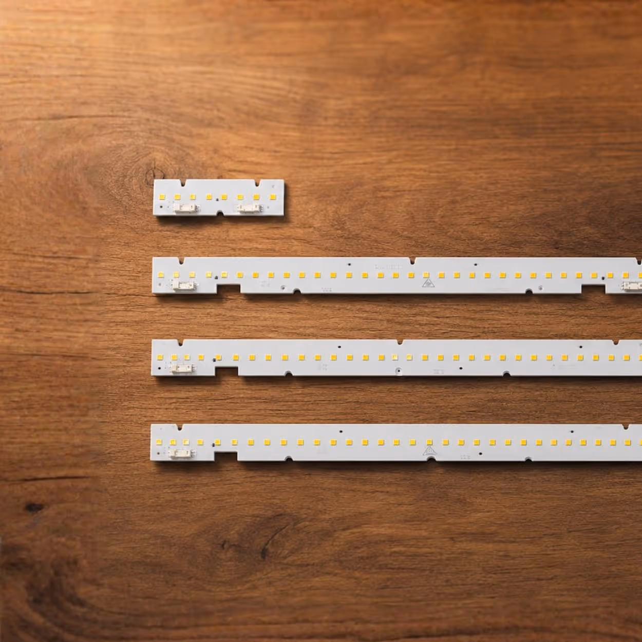 Four LED light strips of varying lengths laid out on a wooden surface.