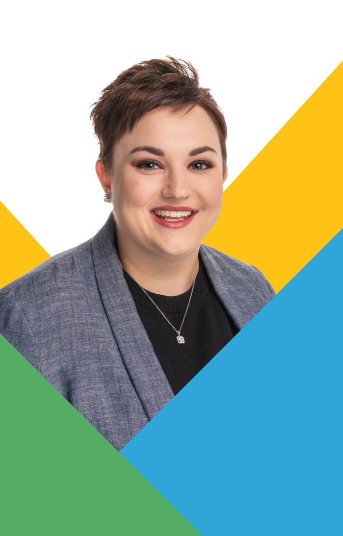 Smiling short-haired woman wearing a gray blazer and necklace with geometric colored background.