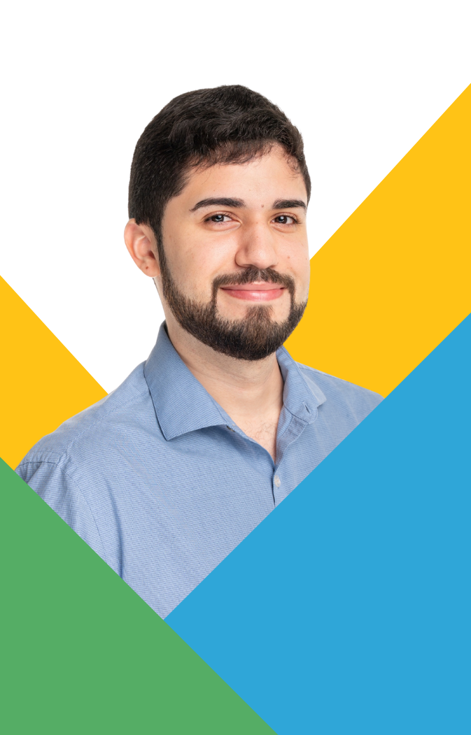 Smiling man with beard wearing a blue shirt with yellow, green, and blue geometric background.