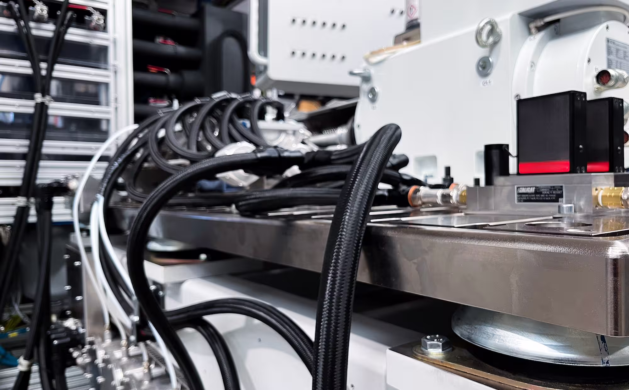 Close-up of industrial machinery with black cables and a metal platform in a factory setting.