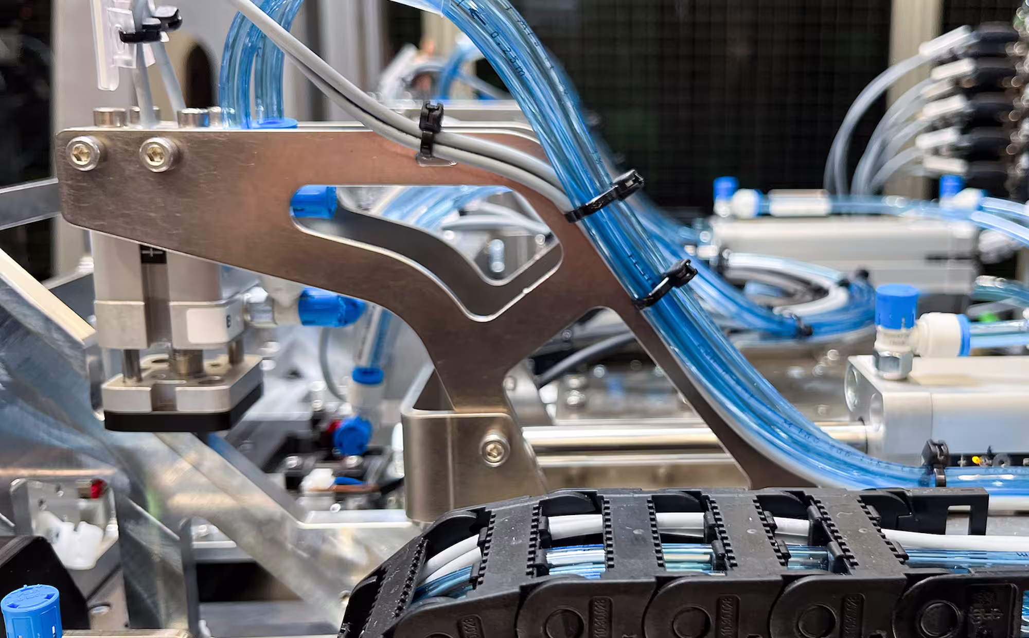 Close-up of industrial machine with metal parts and blue tubing for fluid or air automation system.