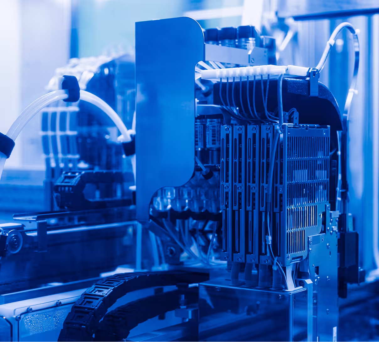 Close-up of blue-lit laboratory automation equipment with tubing and electronic components.