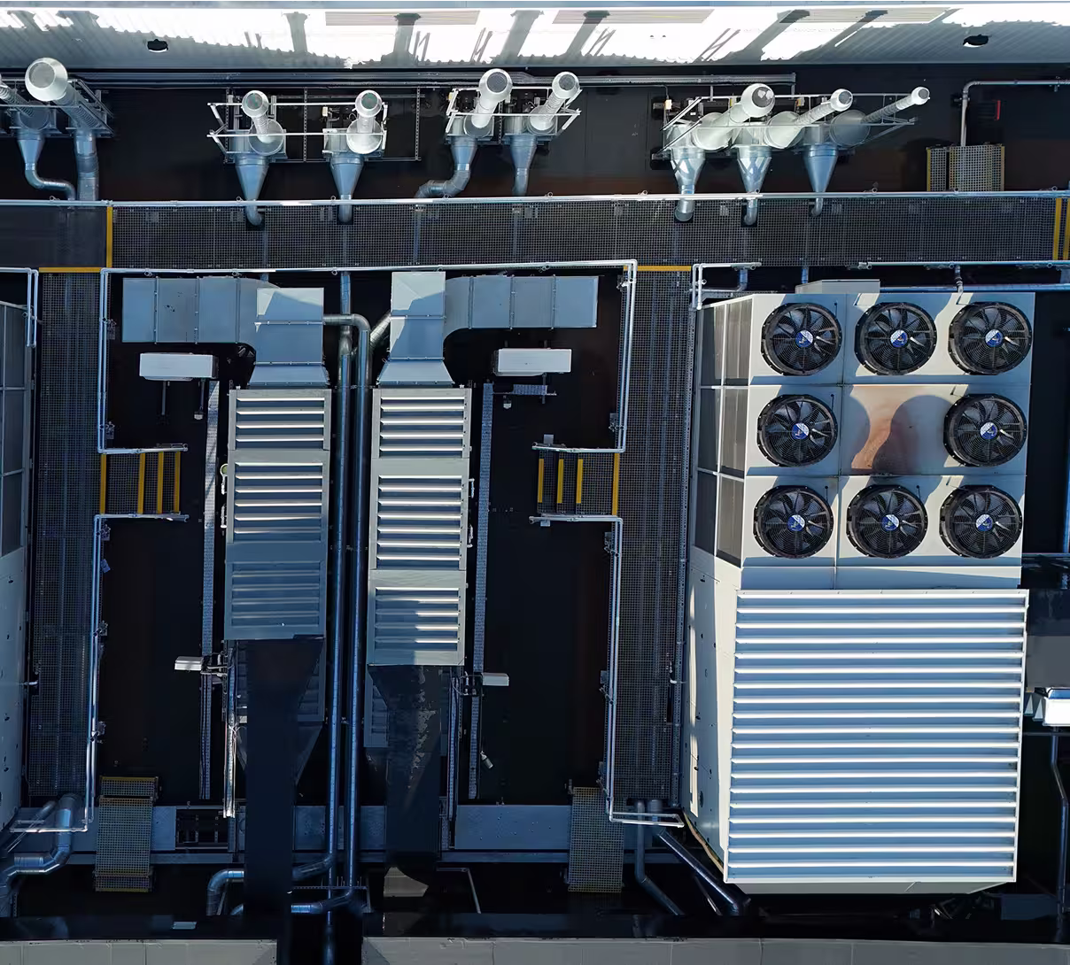 Aerial view of industrial rooftop HVAC units with vents, ducts, and nine cooling fans.