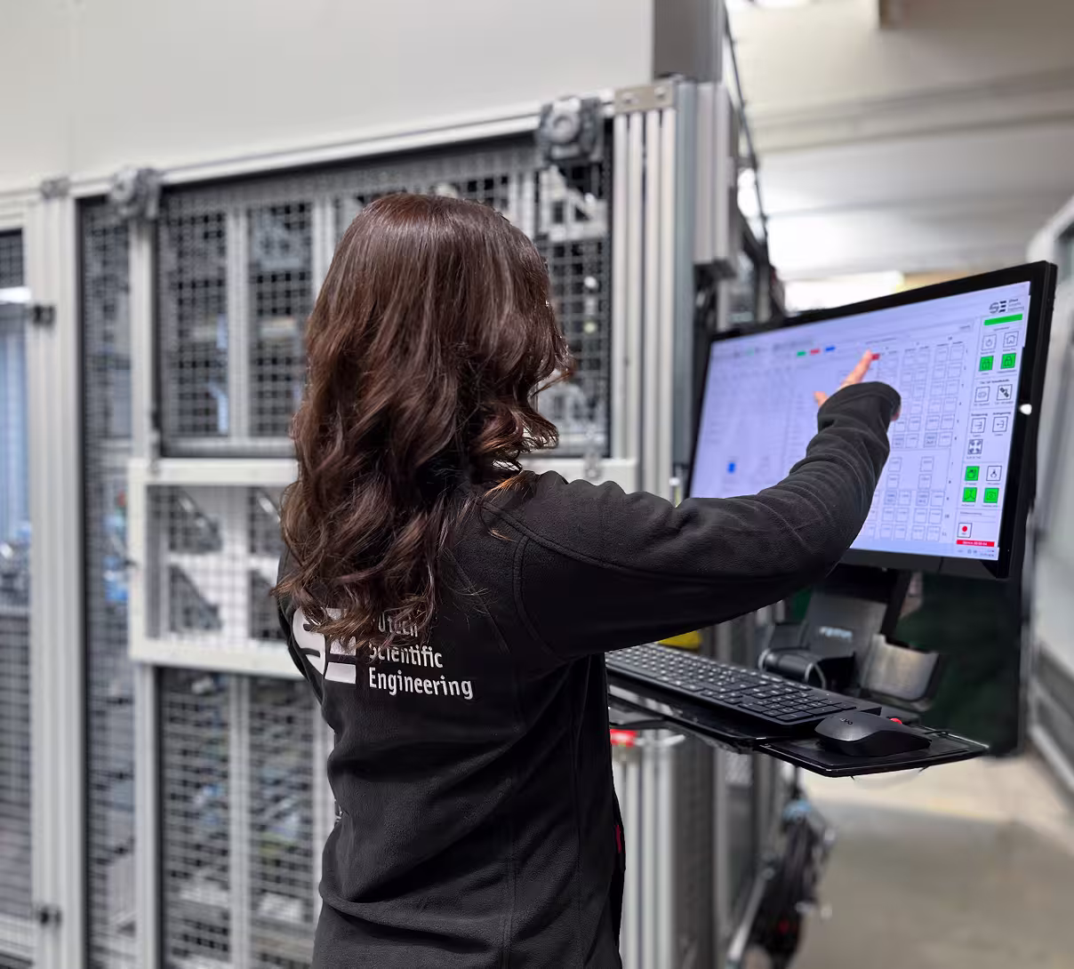 Woman operating a touchscreen control panel for an automated handling system in a modern industrial facility.