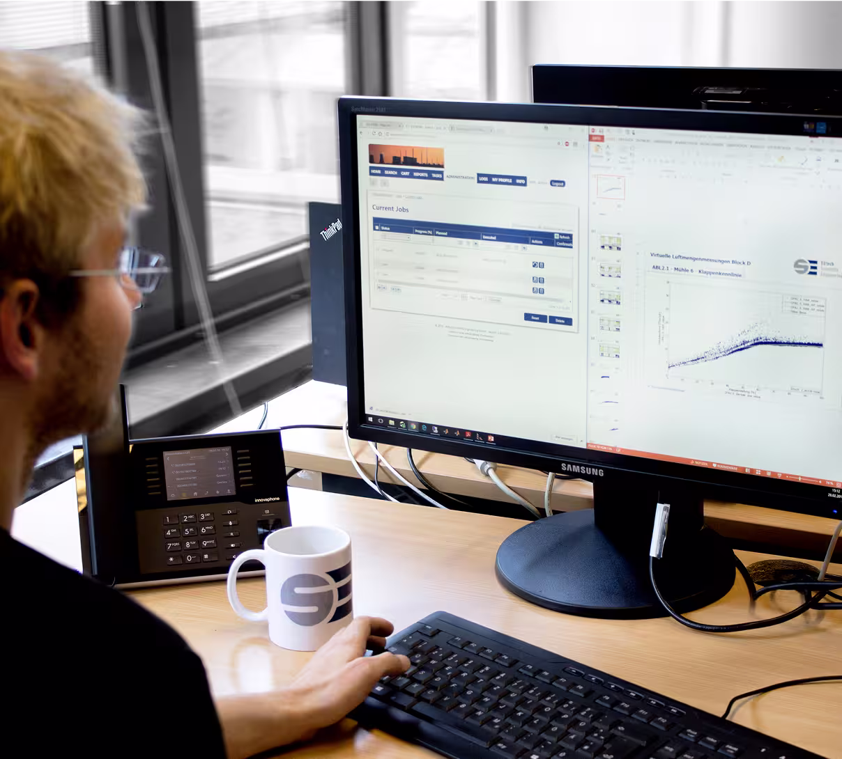 Person managing technical data on a dual-screen workstation with graphs and data visualizations.