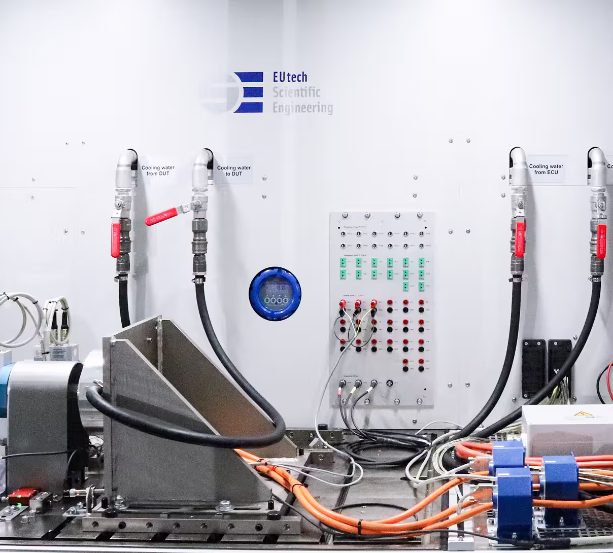 Large enclosed powertrain test bench with control panel and internal components in a clean laboratory environment.
