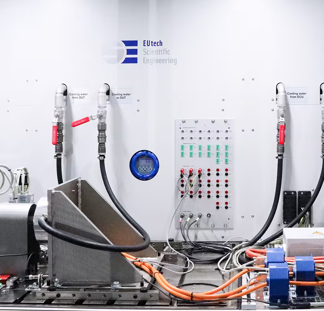 Powertrain test system with labeled cooling water lines and an electronic control panel for laboratory testing.