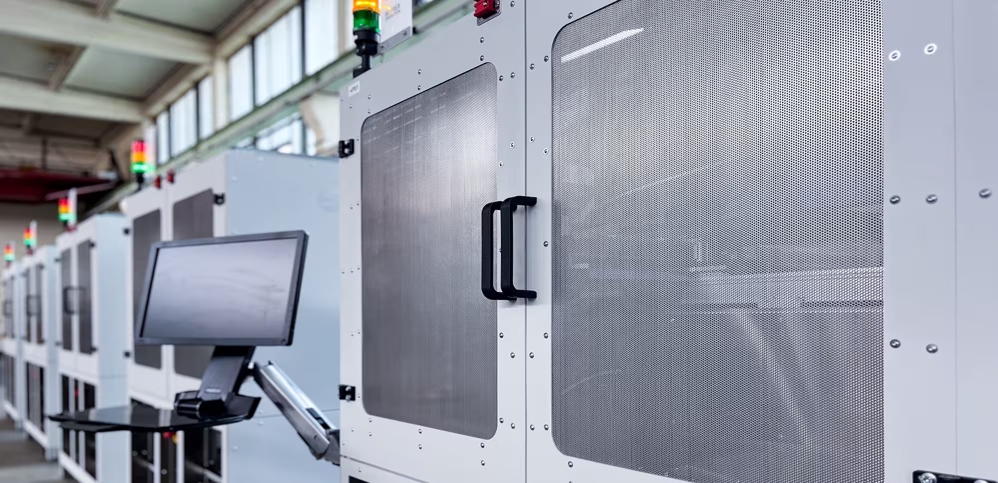 Row of automated SEA test systems with integrated control panels and indicator lights in a factory setting.