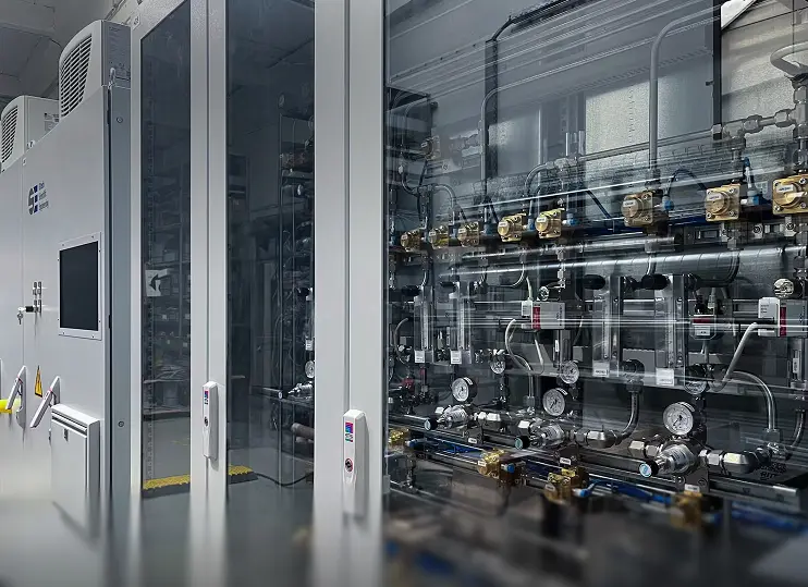 Industrial control panel and piping system with gauges and valves in a clean mechanical room.