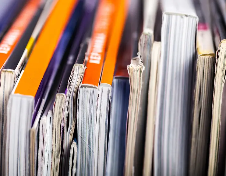 Close-up of various stacked magazines with different colored covers and visible page edges.