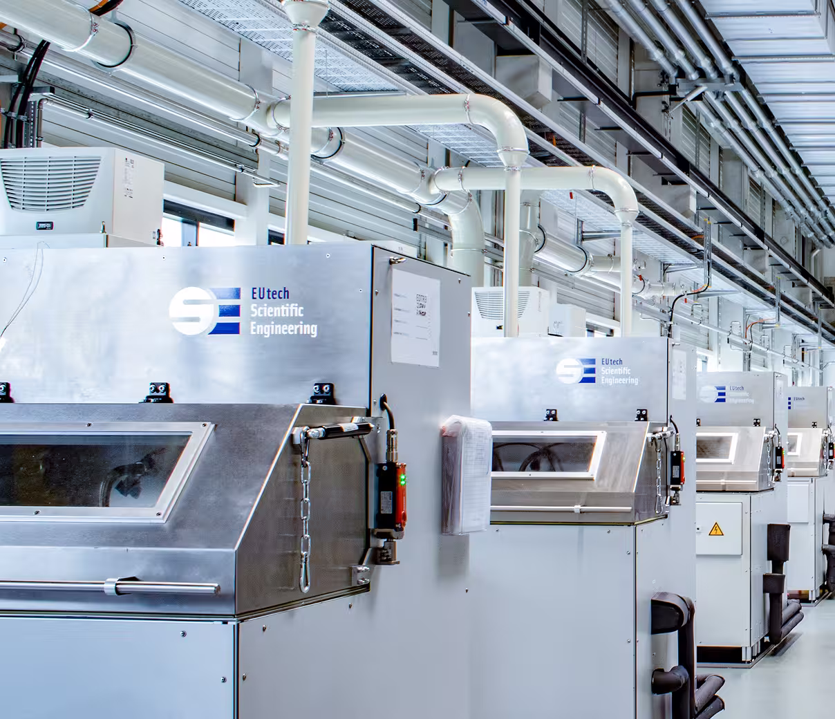 Row of industrial EUtech Scientific Engineering pump test benches in a clean, bright factory setting.